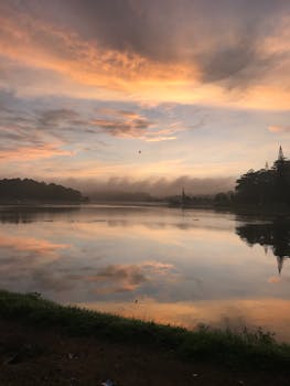 Beautiful sunrise over a calm lake with vibrant skies reflecting in the water, capturing a tranquil morning scene.