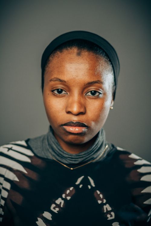 Free Close-up portrait of a young woman with a headscarf, looking directly at camera with neutral background. Stock Photo