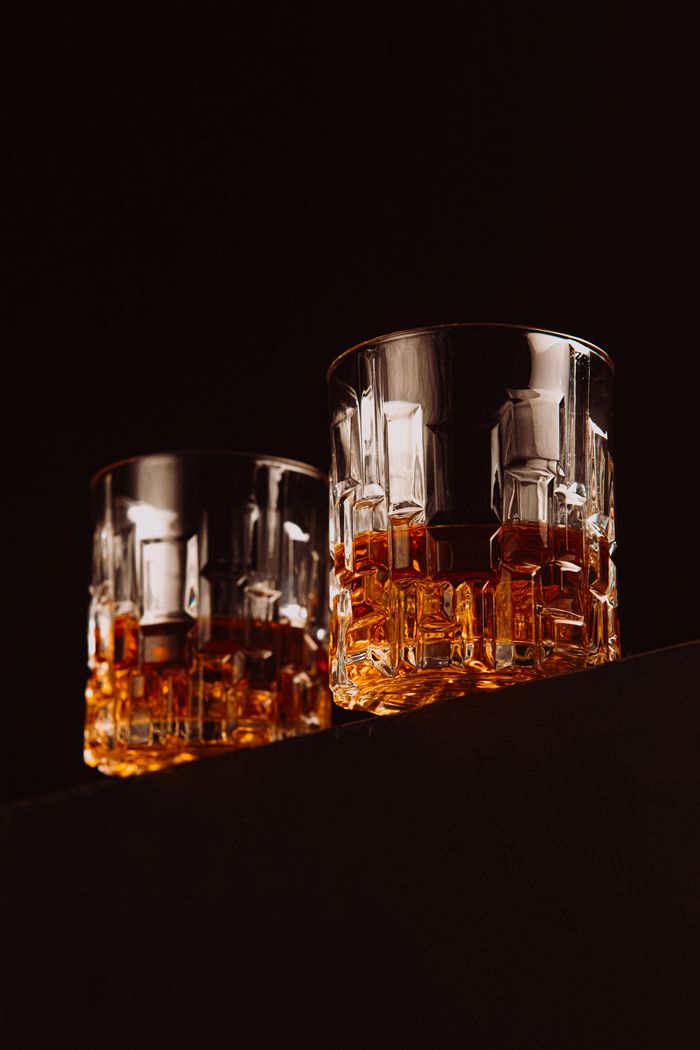 Crystal glasses filled with whiskey on dark surface