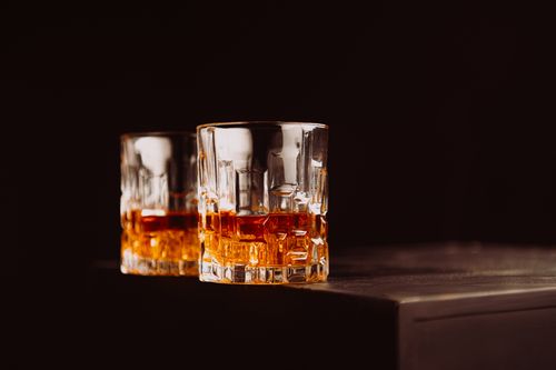Free Two whiskey glasses with amber liquid on a dark surface, creating a cozy atmosphere. Stock Photo