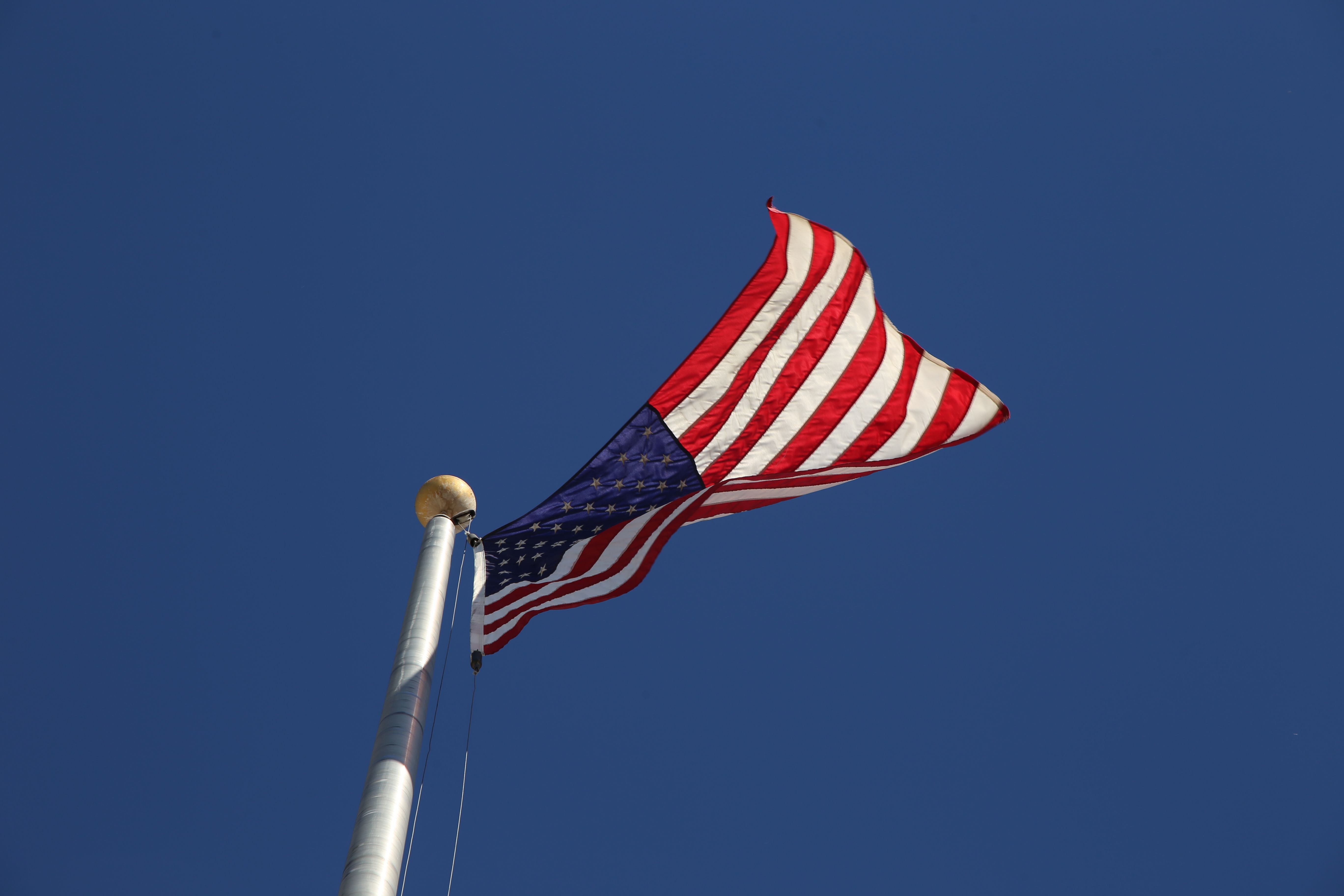 American Flag Against Clear Blue Sky · Free Stock Photo