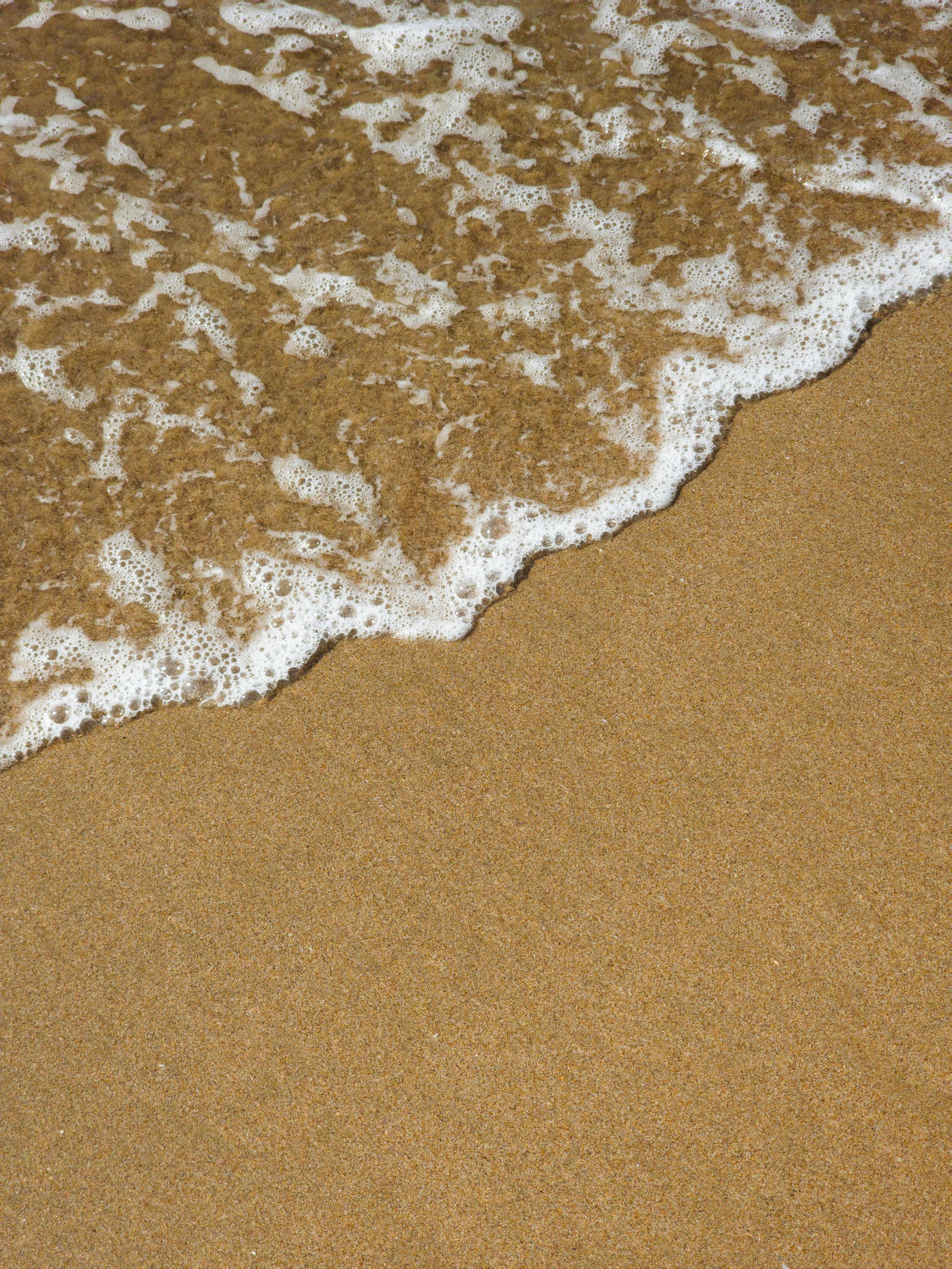 Gratuit Les vagues caressent doucement la plage de sable doré, créant un paysage côtier serein. Photos