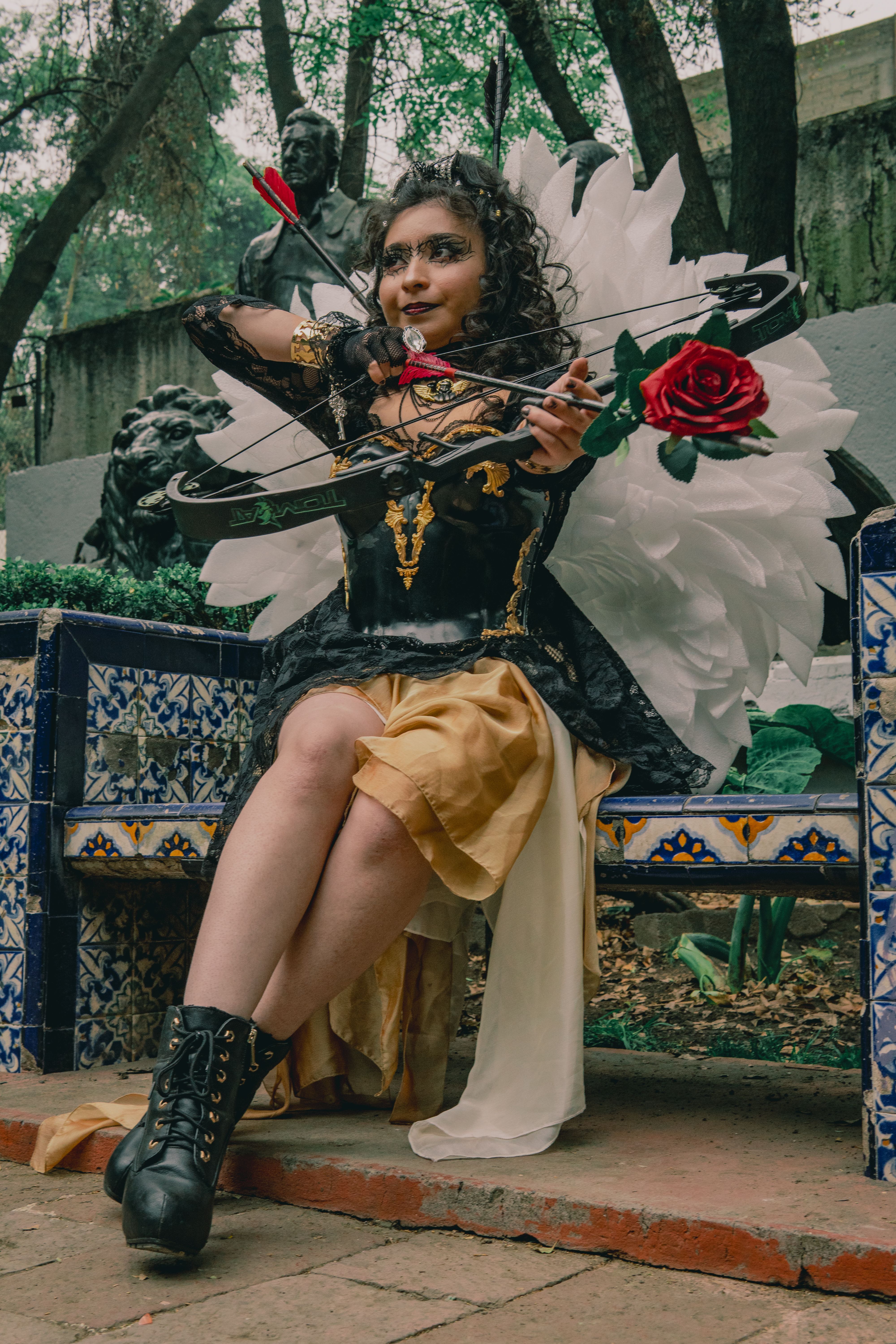 A woman in a detailed carnival costume with angel wings poses outdoors in Mexico City.