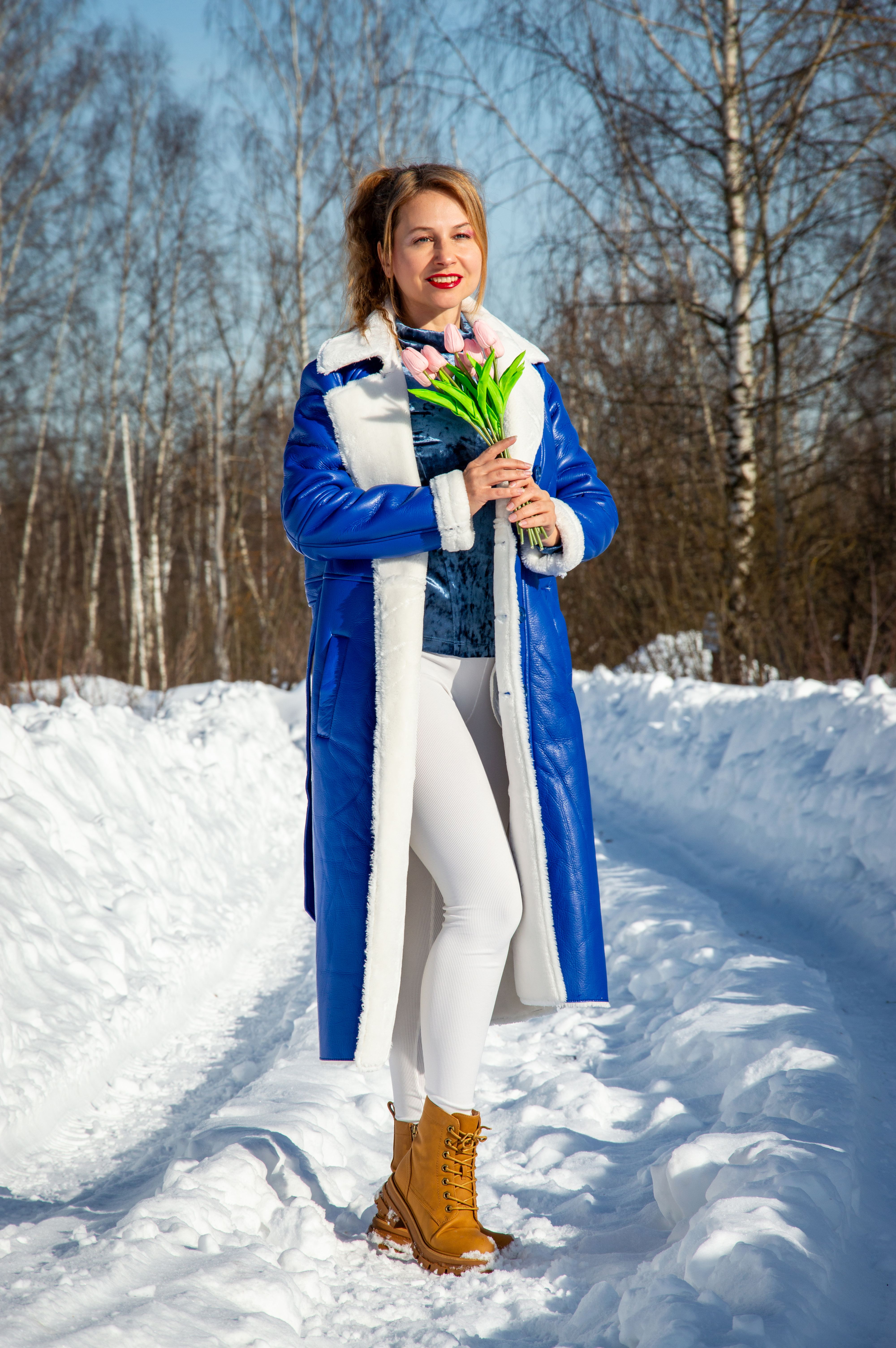 Woman in Blue Coat Holding Flowers in Snowy Landscape · Free Stock Photo