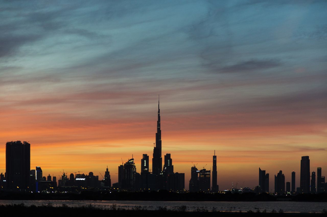 Burj Khalifa and the Dubai skyline silhouetted against an orange sunset