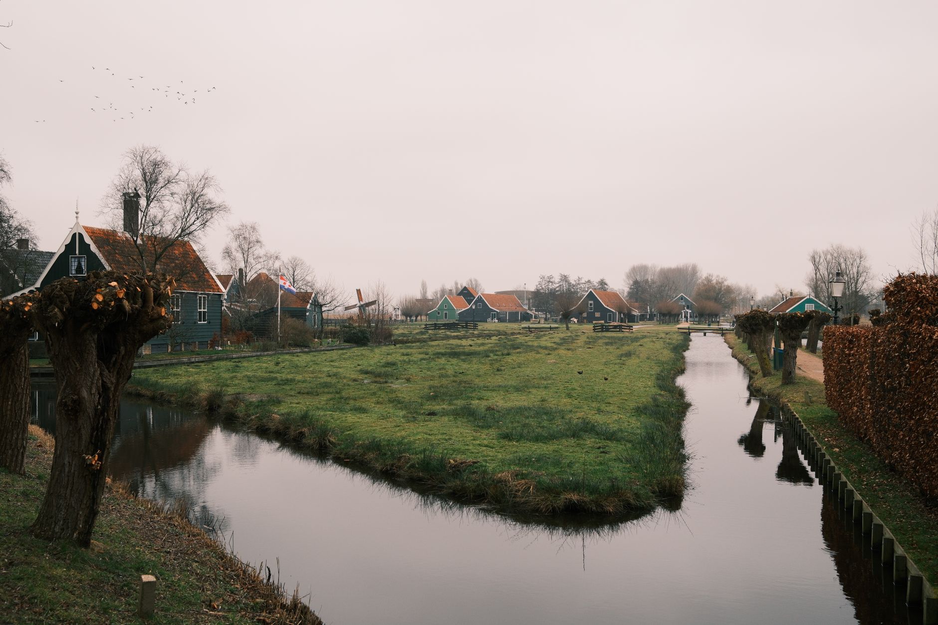 A picturesque Dutch village with traditional houses, a canal, and distant windmill.