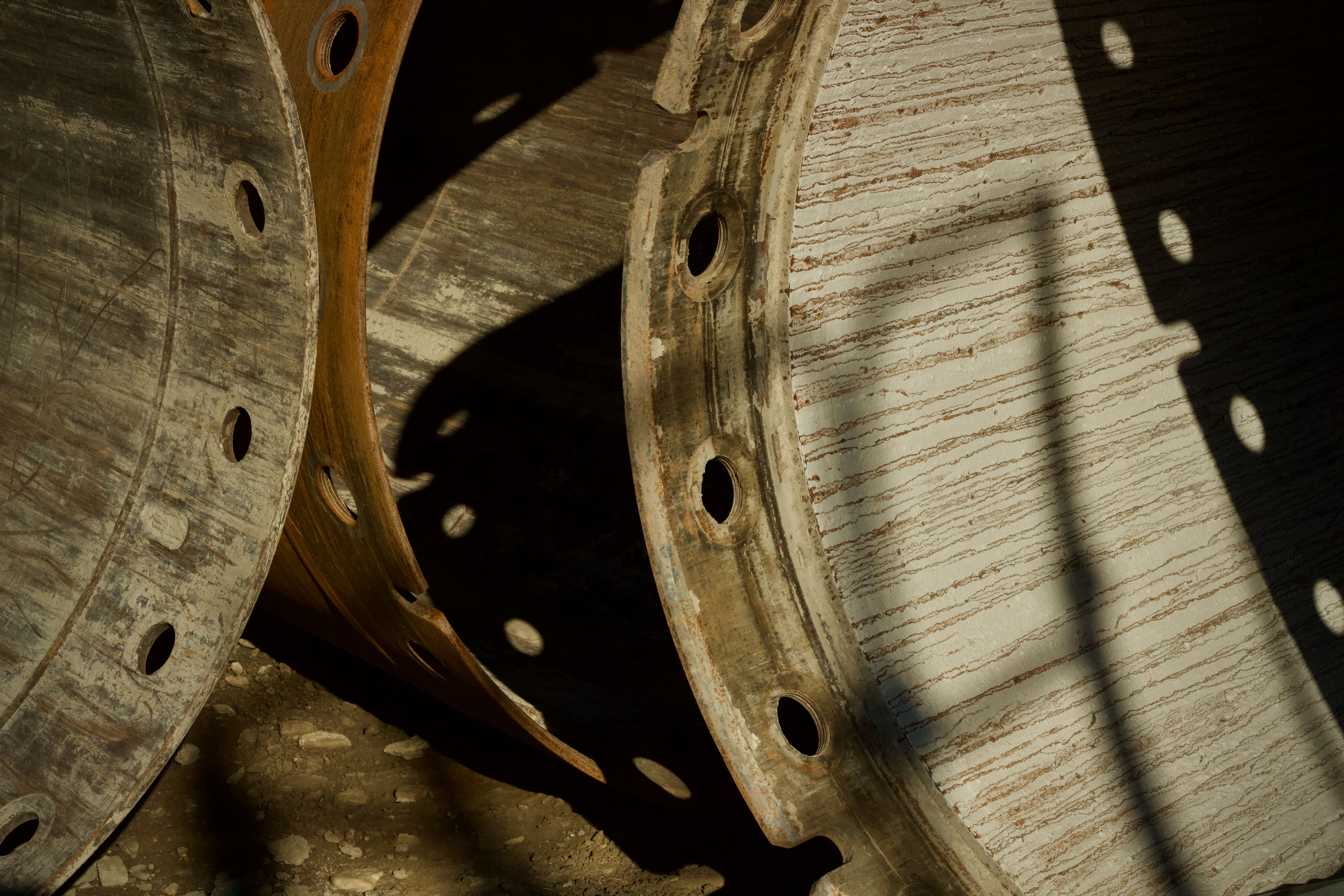 Detailed view of industrial steel pipe flanges with shadows, showcasing texture and craftsmanship.