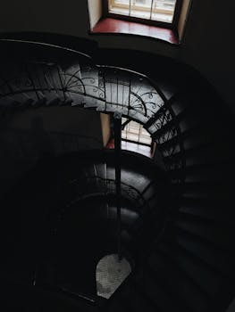 光线从上方窗口洒下，沐浴着螺旋楼梯华丽的栏杆，营造出喜怒无常的气氛