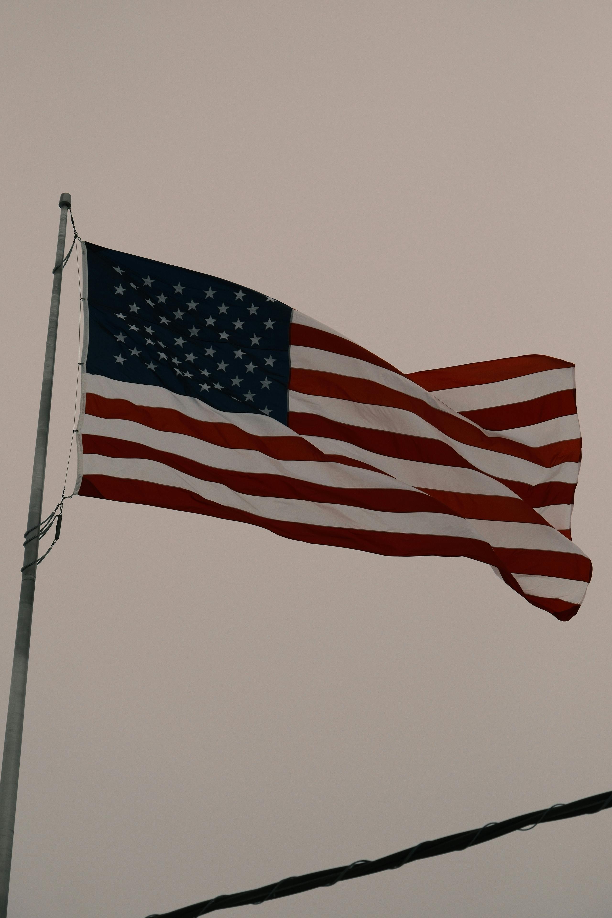 Free United States flag waving on a pole, symbolizing patriotism and freedom. Stock Photo