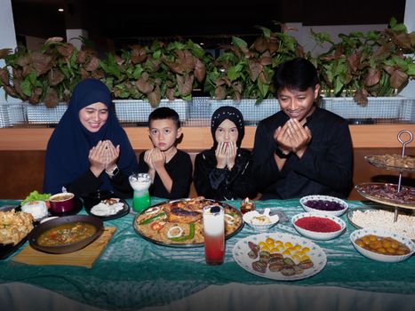 A family of four prays before enjoying a traditional festive meal indoors.