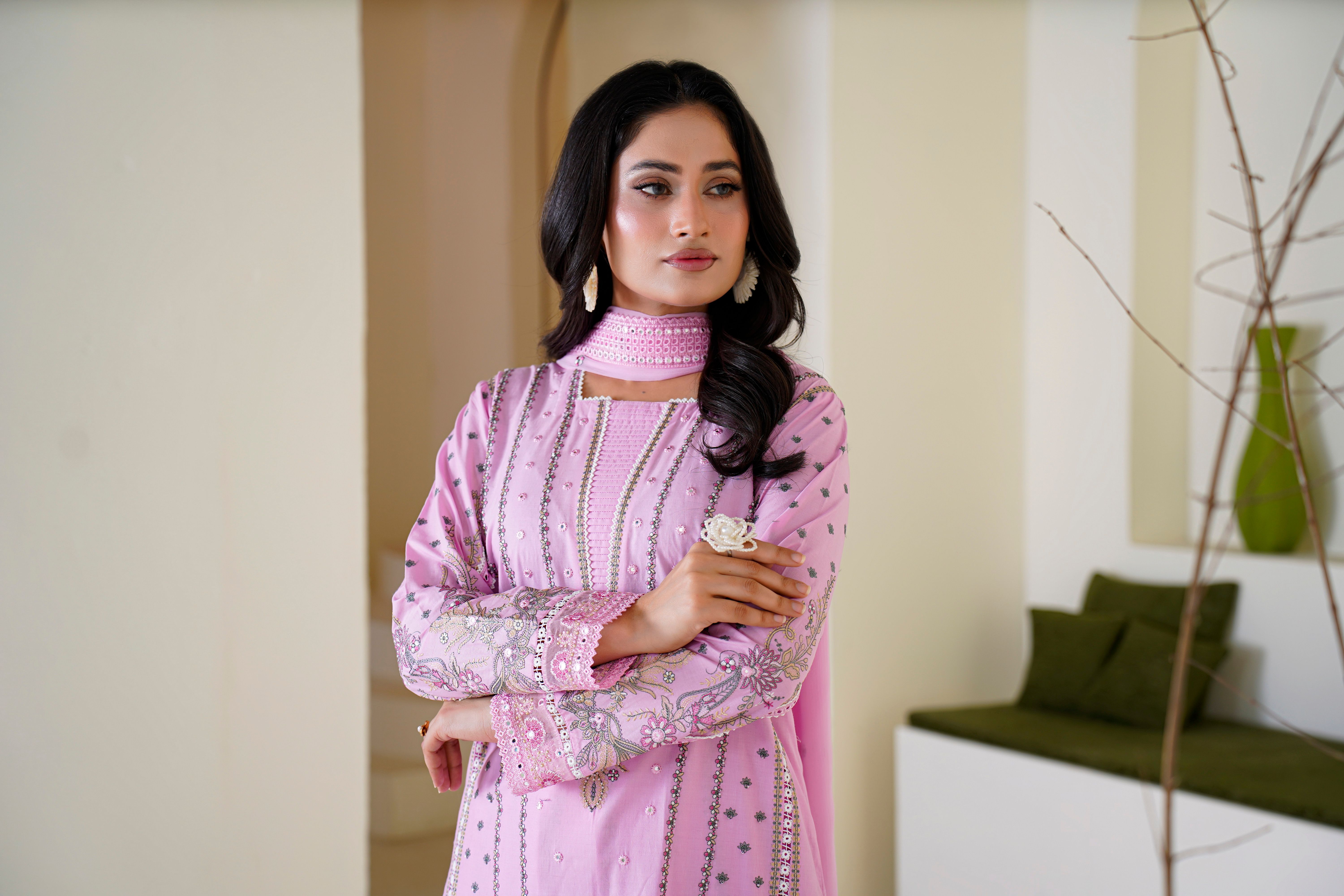A woman elegantly dressed in a light-colored embroidered cross slub lawn outfit, showcasing intricate floral embroidery under soft sunlight.