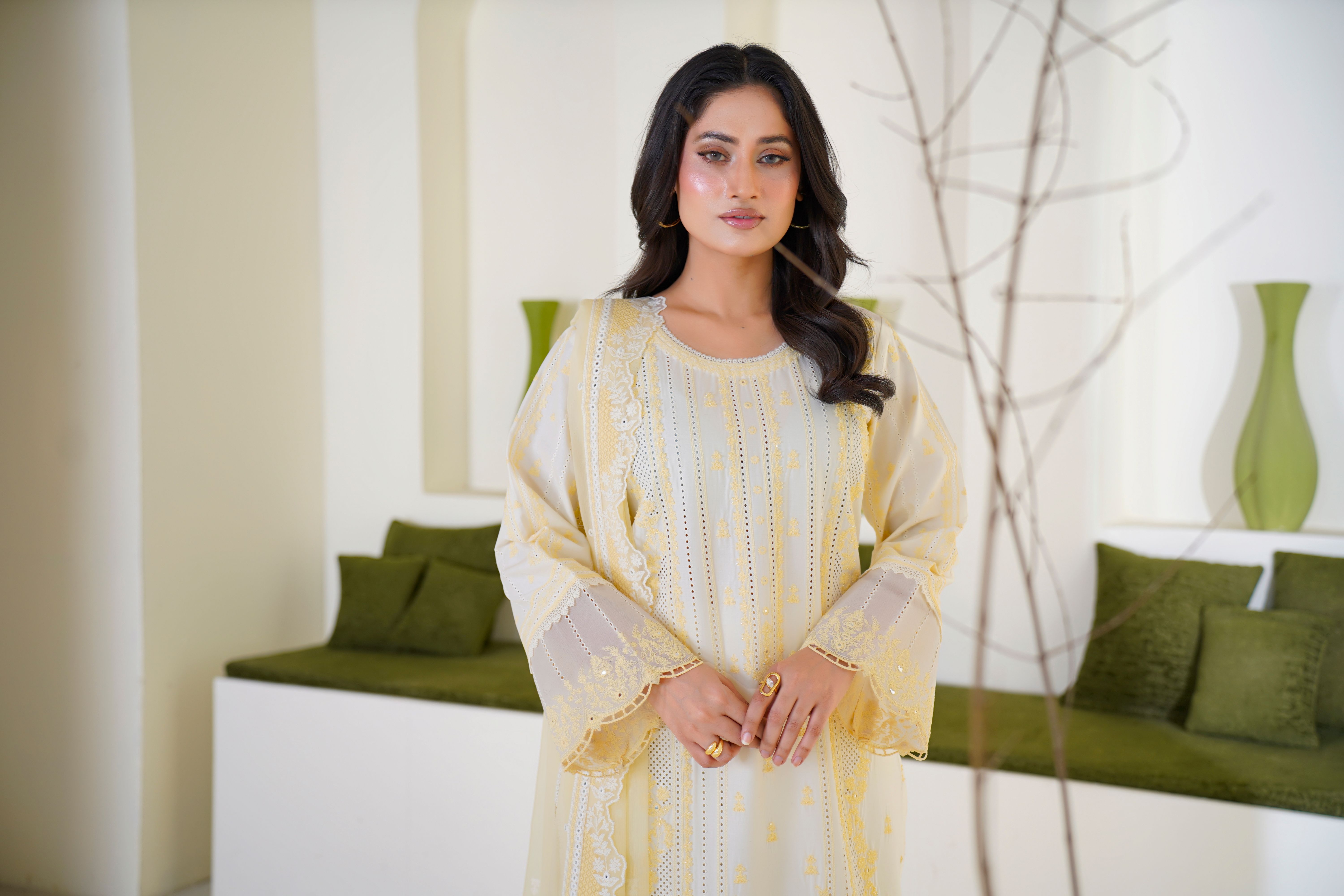 Elegant woman wearing embroidered eastern attire, posing indoors.