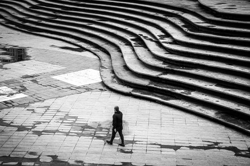 Free A lone person walks beside geometric steps in a black and white urban Istanbul scene. Stock Photo