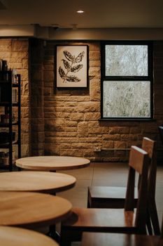Warm and inviting café interior showcasing wooden tables and chairs with a stone wall backdrop.