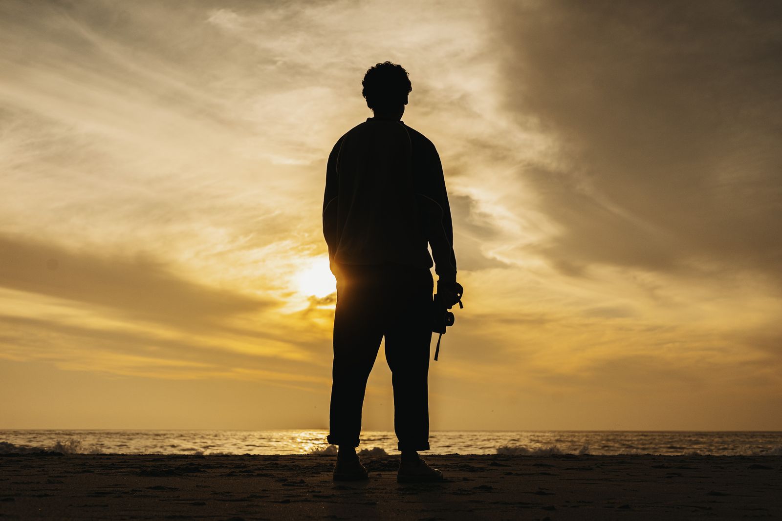 Photographer silhouetted against a stunning sunset on a Cape Town beach.