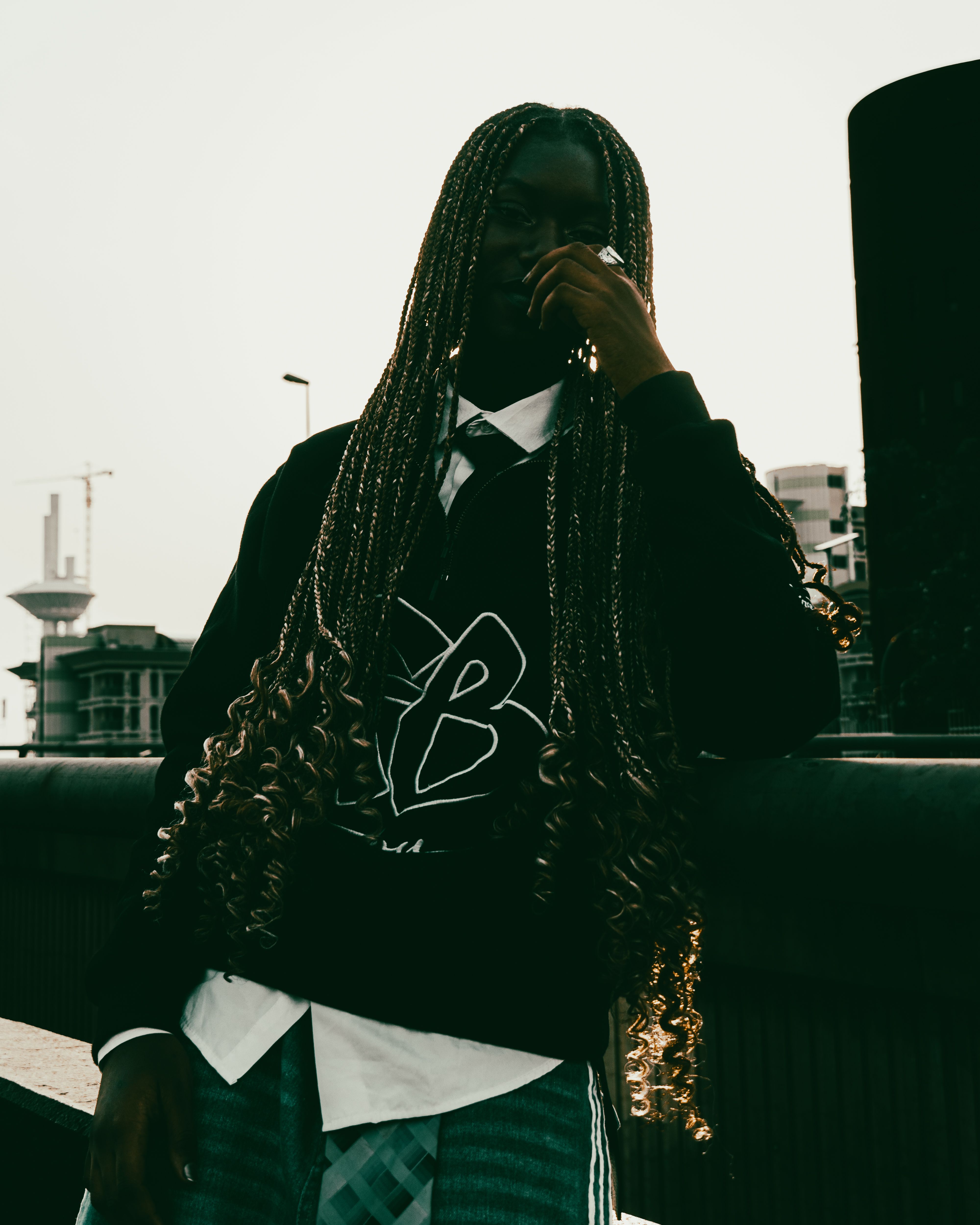 Silhouette of a person with braided hair in an urban Abuja setting during the day.
