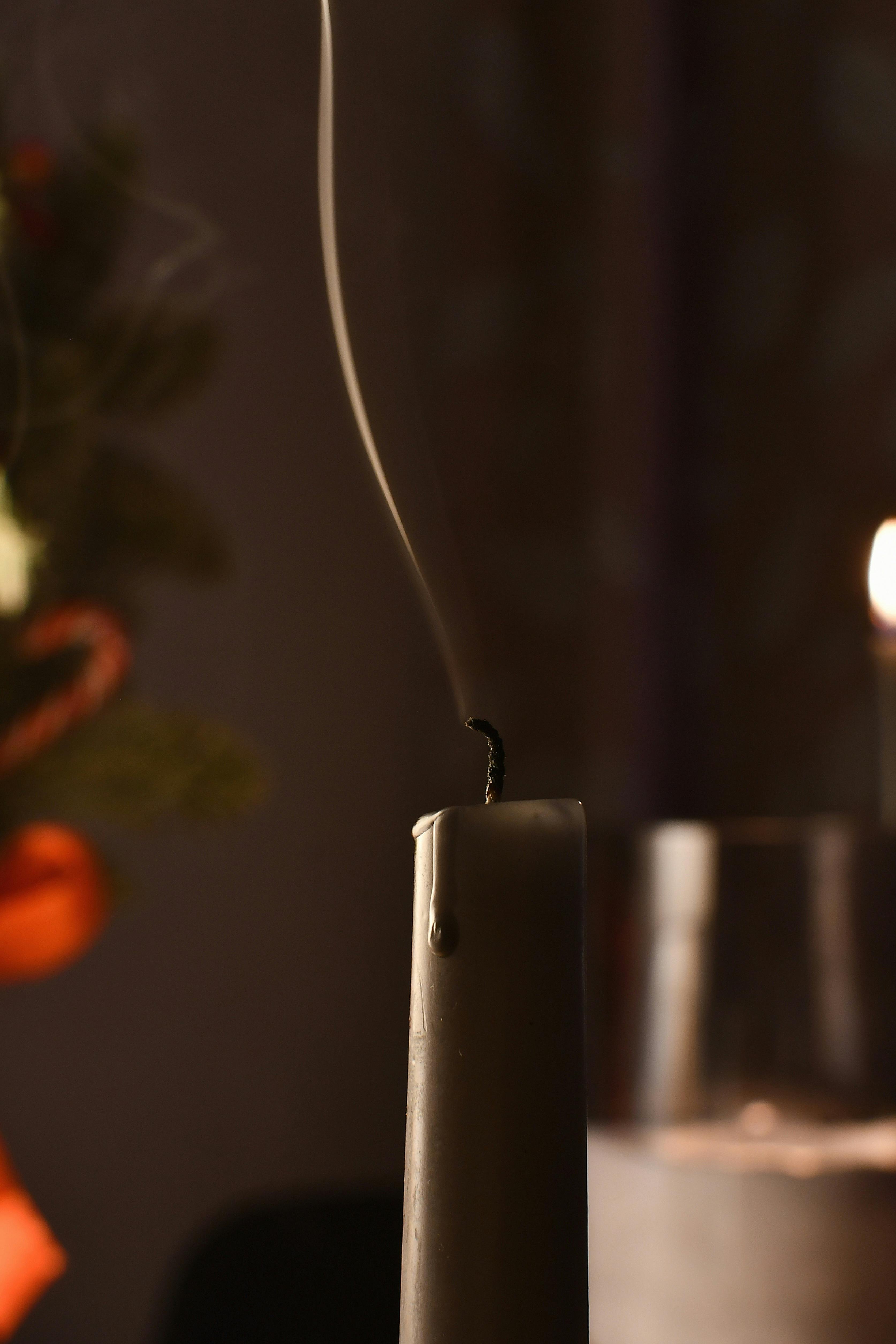 Free Close-up of smoke rising from a recently extinguished candle in a dimly lit setting with warm tones. Stock Photo