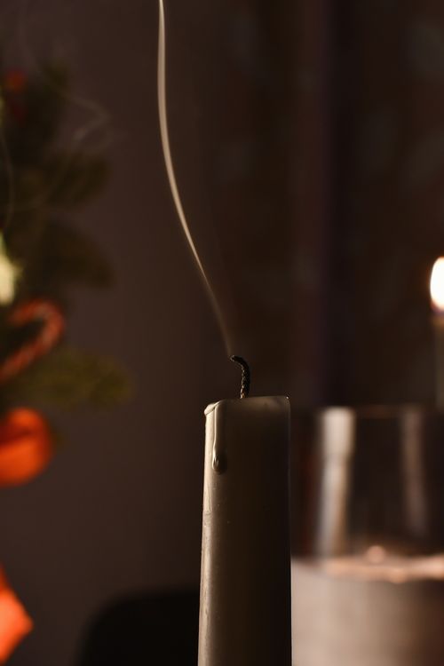 Free Close-up of smoke rising from a recently extinguished candle in a dimly lit setting with warm tones. Stock Photo
