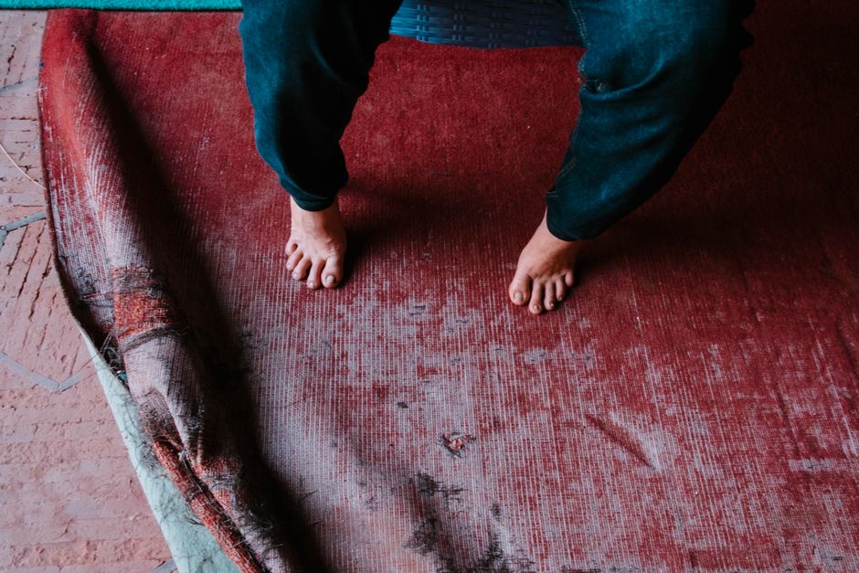 Bare feet on a worn vintage rug in Lahore, creating a rustic and cozy atmosphere.