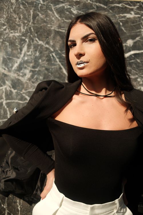 Free Fashionable woman in black outfit posing confidently against a marble background. Stock Photo