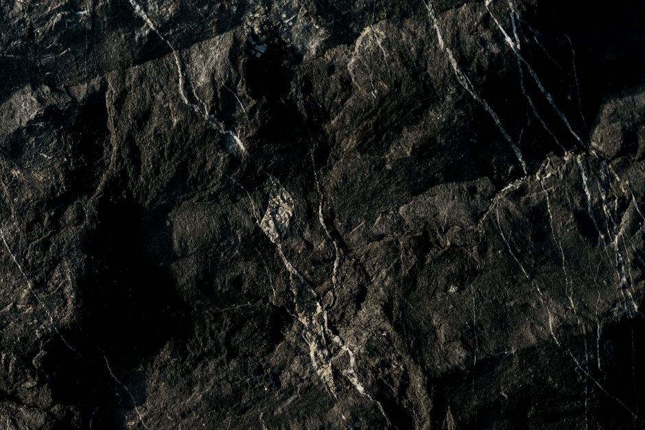 Closeup of a dark marble stone surface with natural textures and patterns for background use.