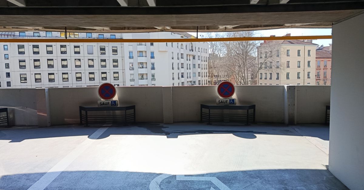 An empty parking garage level with visible disability parking and no parking signs outside city buildings.