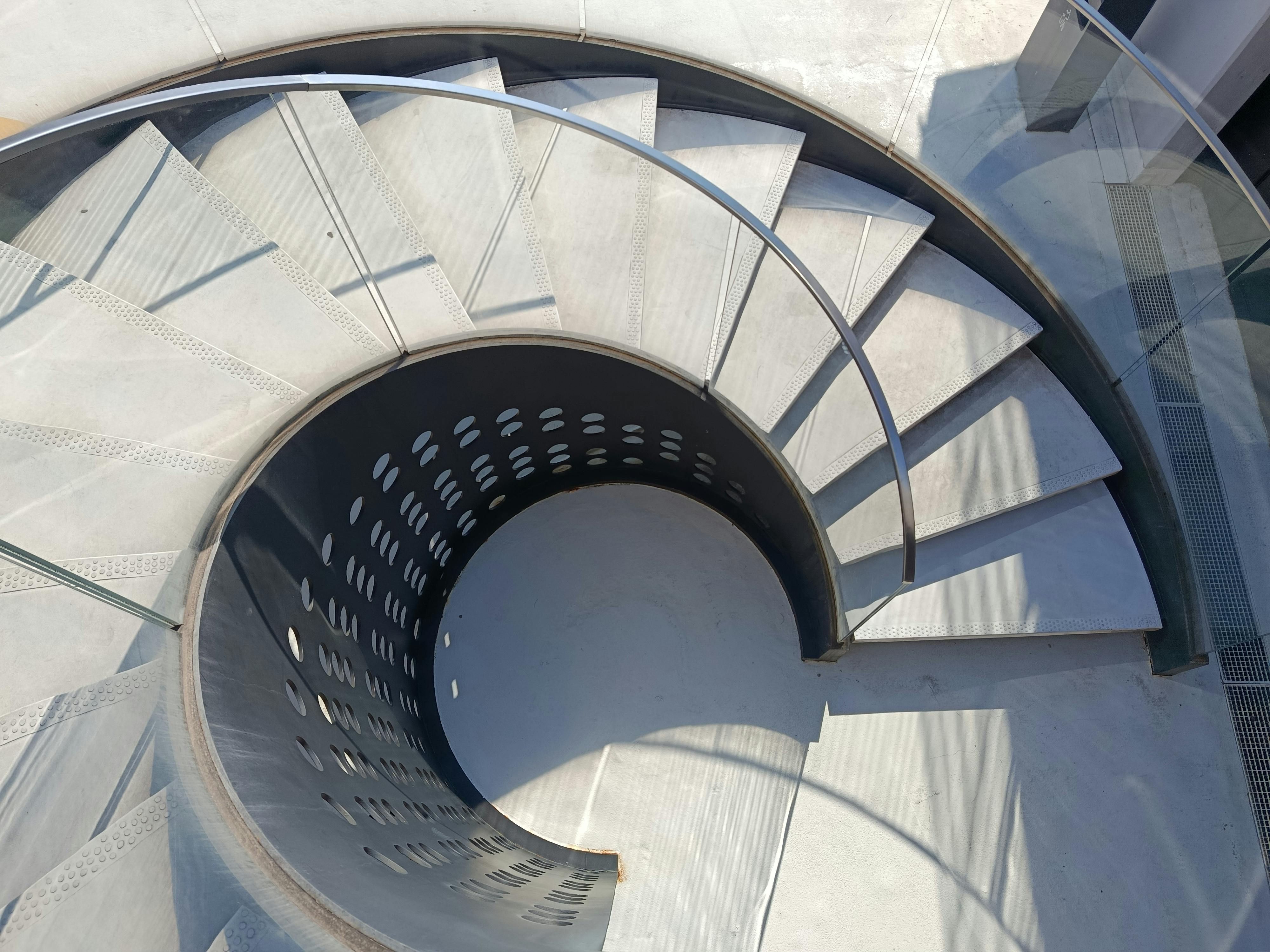 無料 日光の下で金属製の手すりが付いたモダンな螺旋階段の航空写真。 写真素材