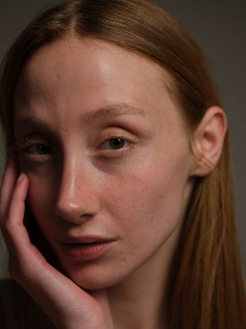 Free A pensive young woman with long hair in a close-up portrait, indoors. Stock Photo