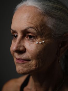 Artistic portrait featuring a senior woman with visible skincare elements. Captures aging gracefully.