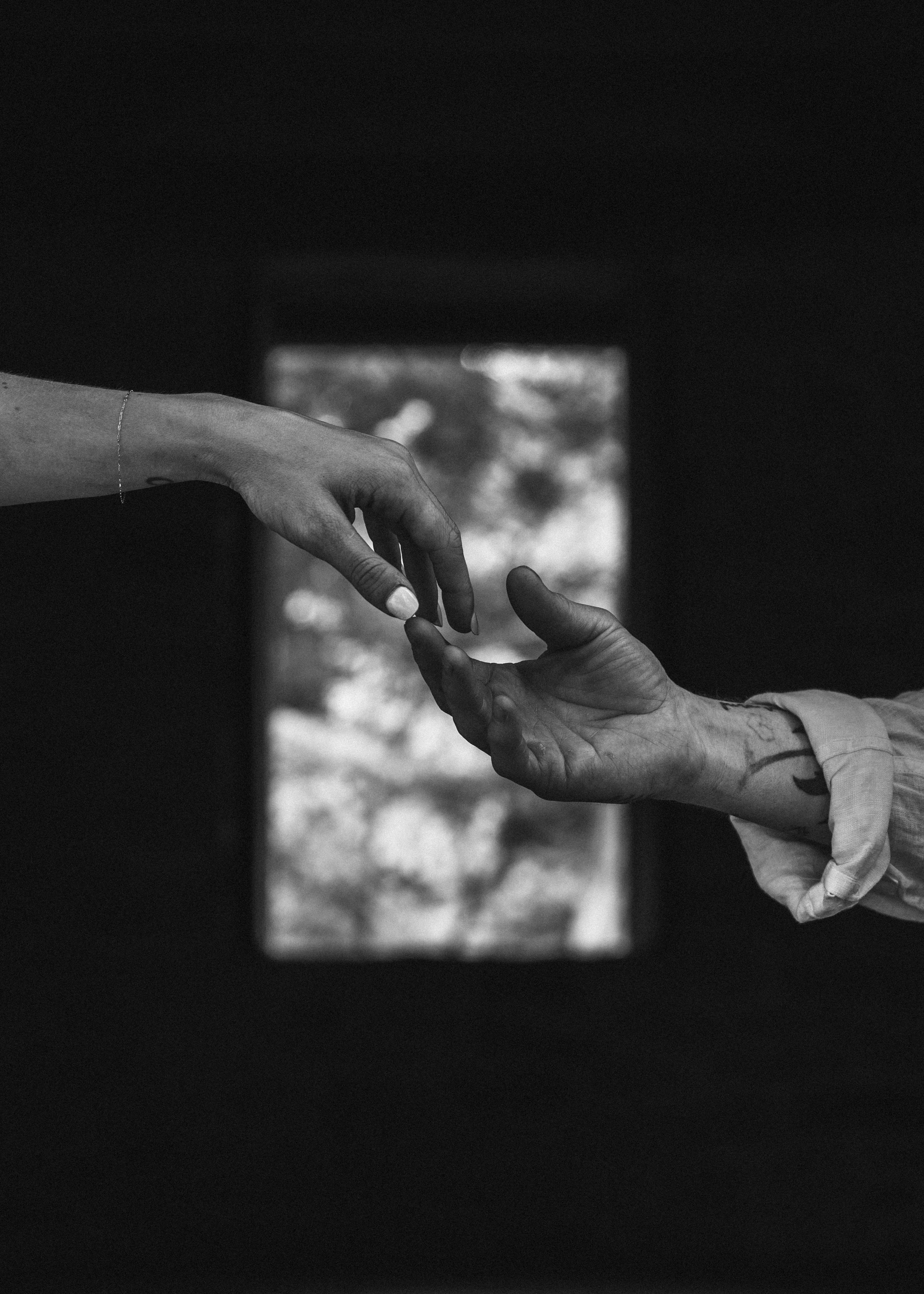 Gratis Immagine in bianco e nero di due mani che si tendono, a simboleggiare connessione e contatto. Foto a disposizione