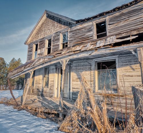 Free A dilapidated farmhouse stands in snowy landscape, capturing nostalgic rural decay. Stock Photo