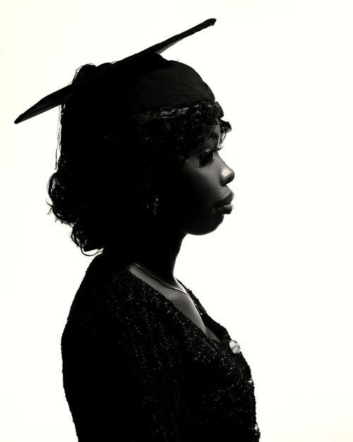 Free Artistic silhouette of an African graduate wearing a cap and gown, side view. Stock Photo