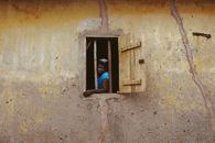 A woman gazes out of a rustic window in a traditional building in Ife, Nigeria.