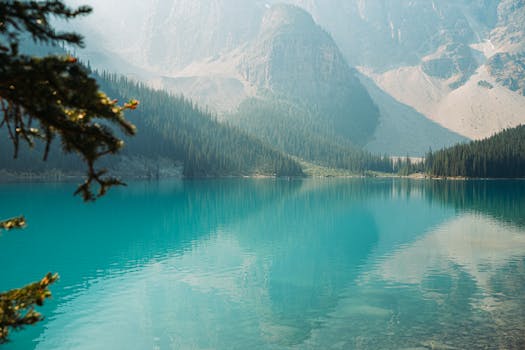 A breathtaking view of a turquoise lake surrounded by lush forests and towering mountains.