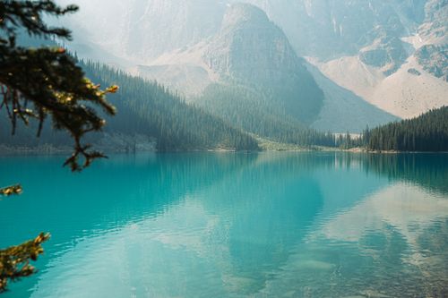 Free A breathtaking view of a turquoise lake surrounded by lush forests and towering mountains. Stock Photo