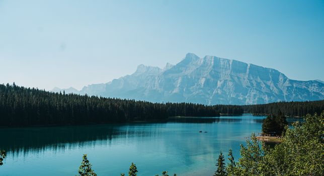 A breathtaking view of a clear lake with majestic mountains and dense forests at Banff National Park.