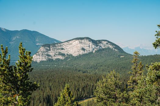 Scenic view of a mountain range with lush green forest under a clear blue sky.