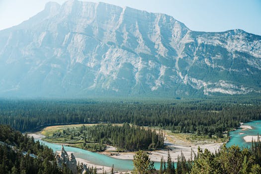 A breathtaking aerial view of Banff National Park with a river and mountain backdrop under clear skies.