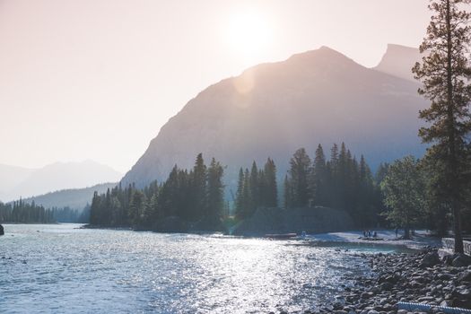 Serene river scene with mountains and trees at sunrise, ideal for nature and travel themes.