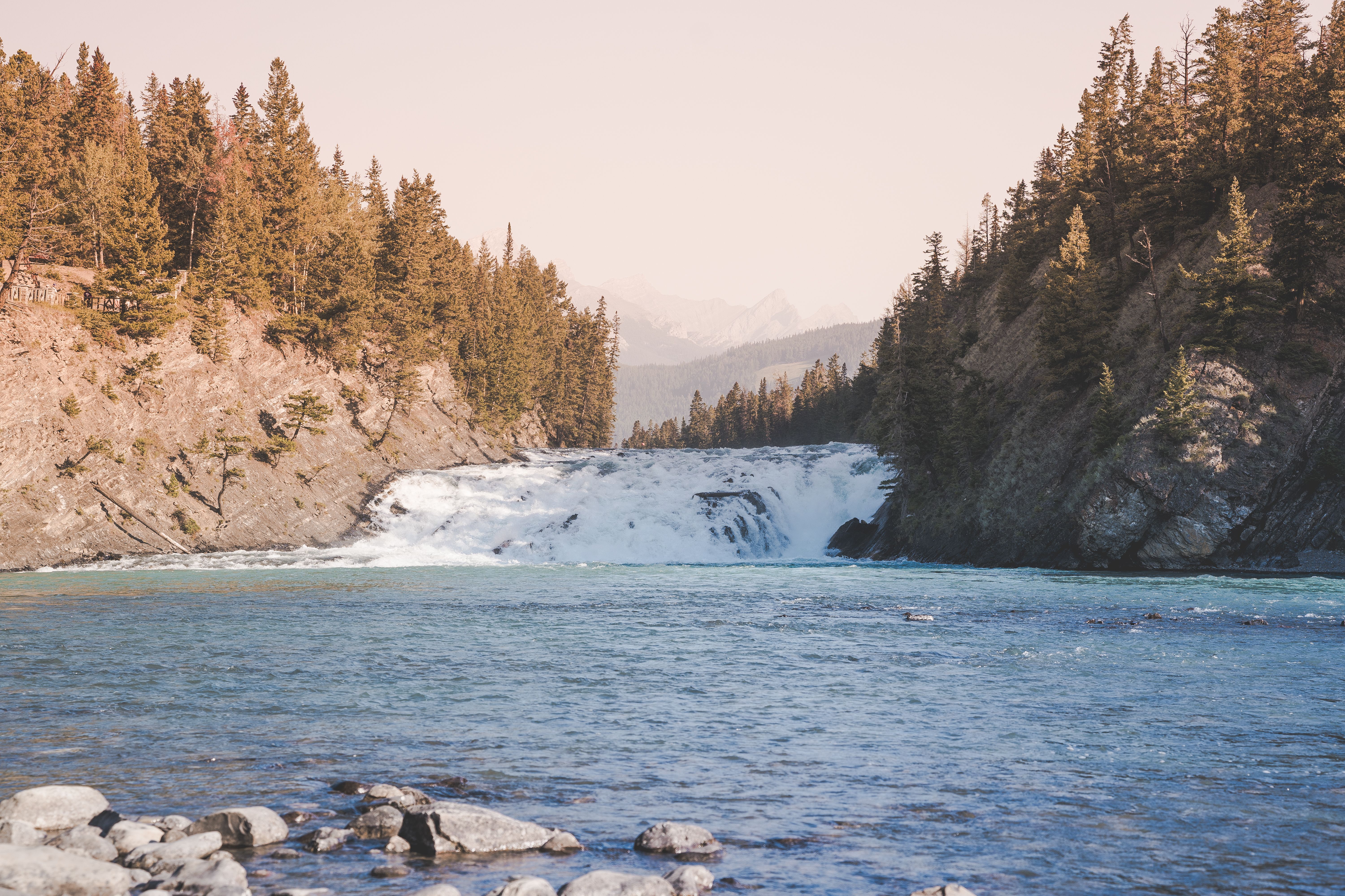 Picturesque view of Bow Falls surrounded by lush evergreen forests in Banff National Park.