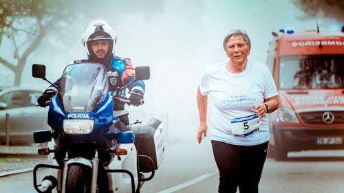 Man in Motorcycle Escort A Old Woman With A Red Ambulance