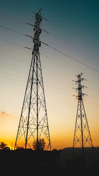 夕阳映衬着高大的输电塔，凸显了能源基础设施
