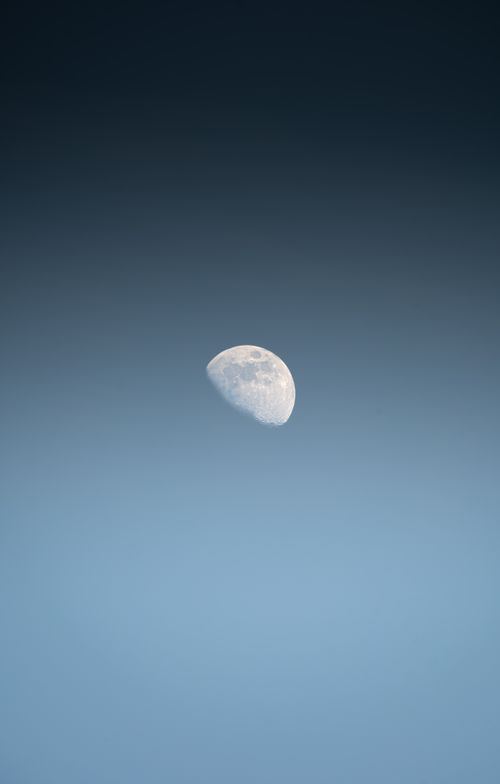 Free A serene crescent moon set against a clear blue sky, capturing a calm and peaceful atmosphere. Stock Photo