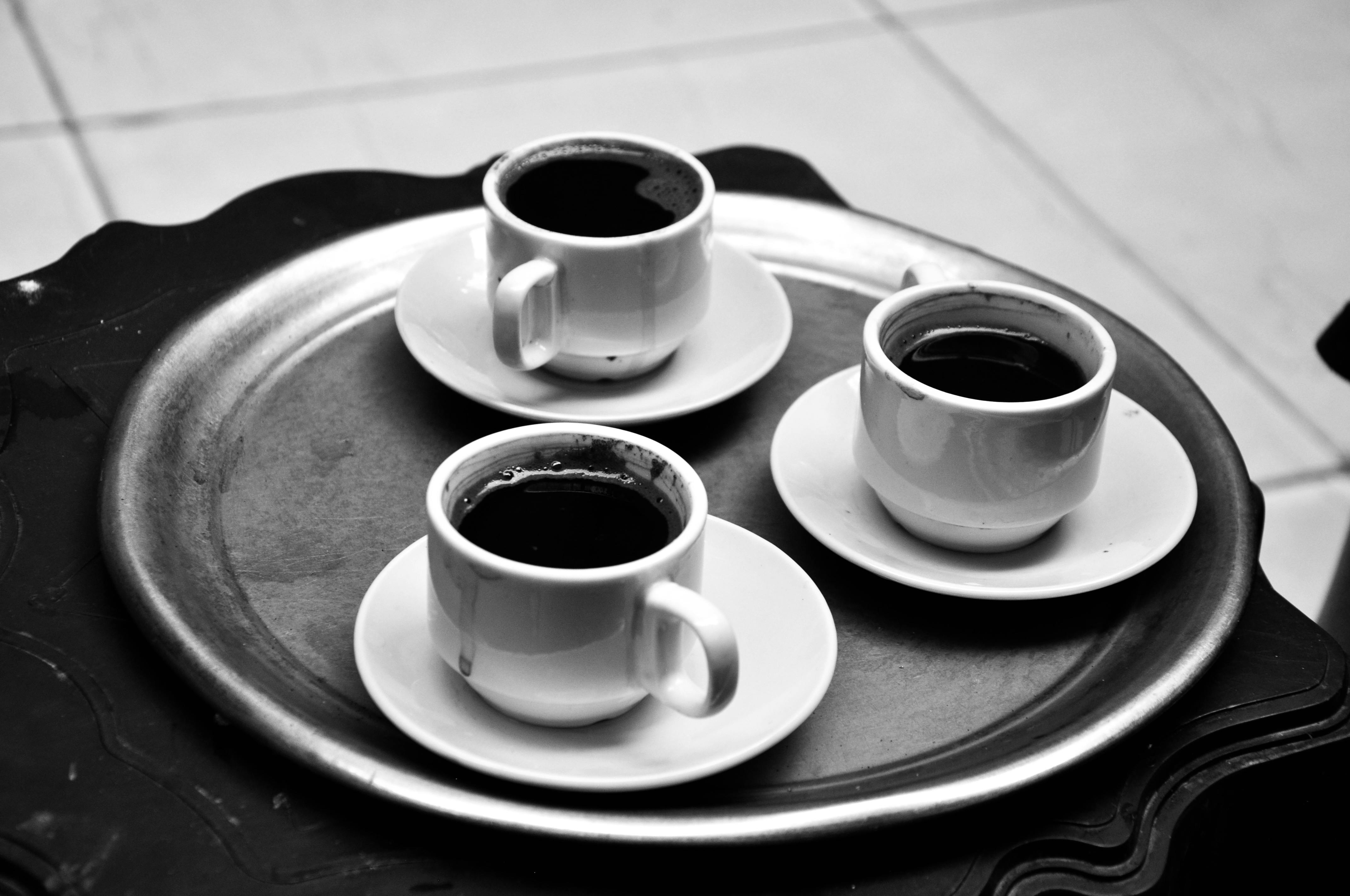 Gratis Tres tazas de café colocadas en una bandeja, capturadas en un estilo clásico en blanco y negro. Foto de stock