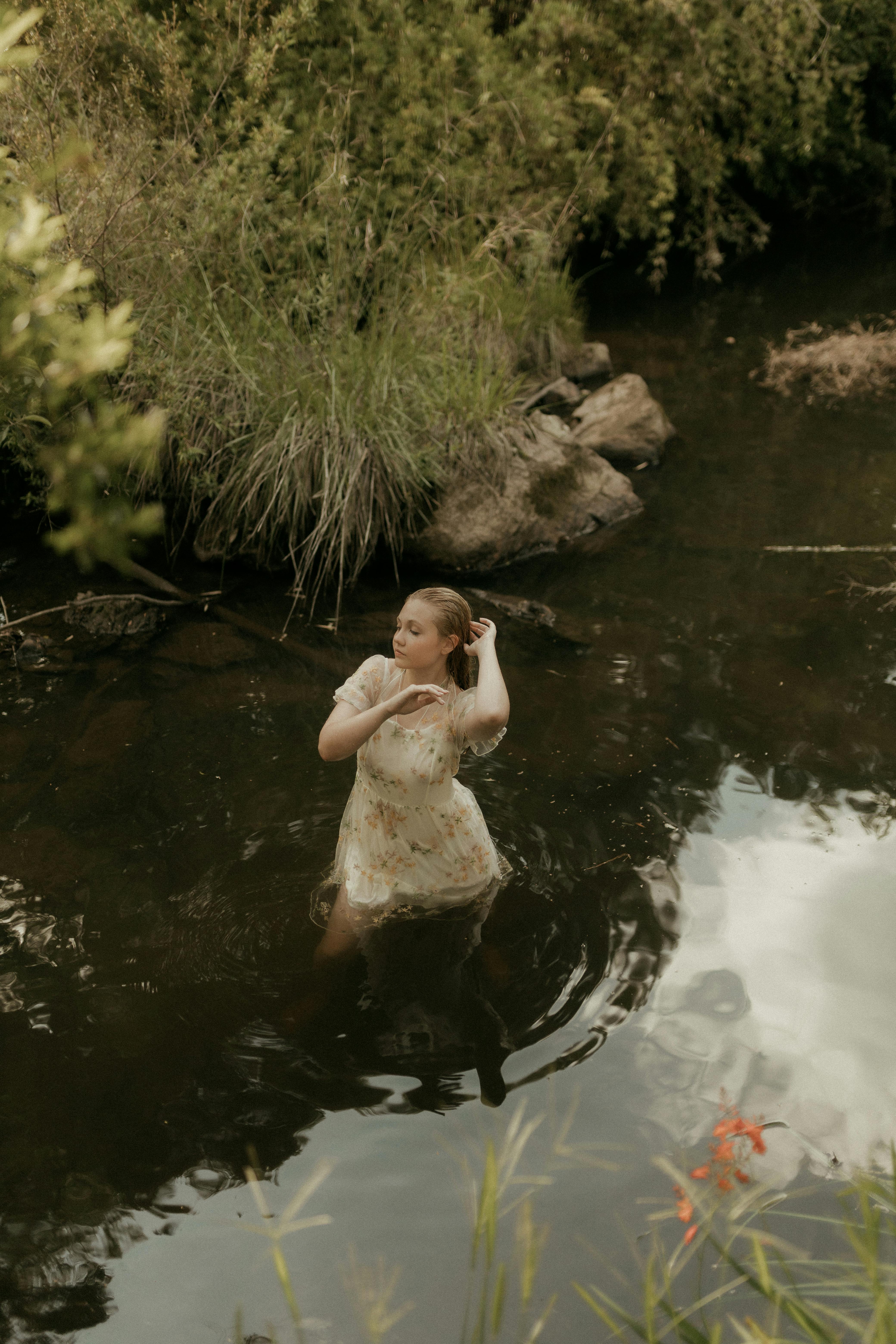 [ColoSach]-graceful-woman-wades-in-a-serene-river-surrounded-by-lush-greenery.-summer-day,-nature's-beauty.