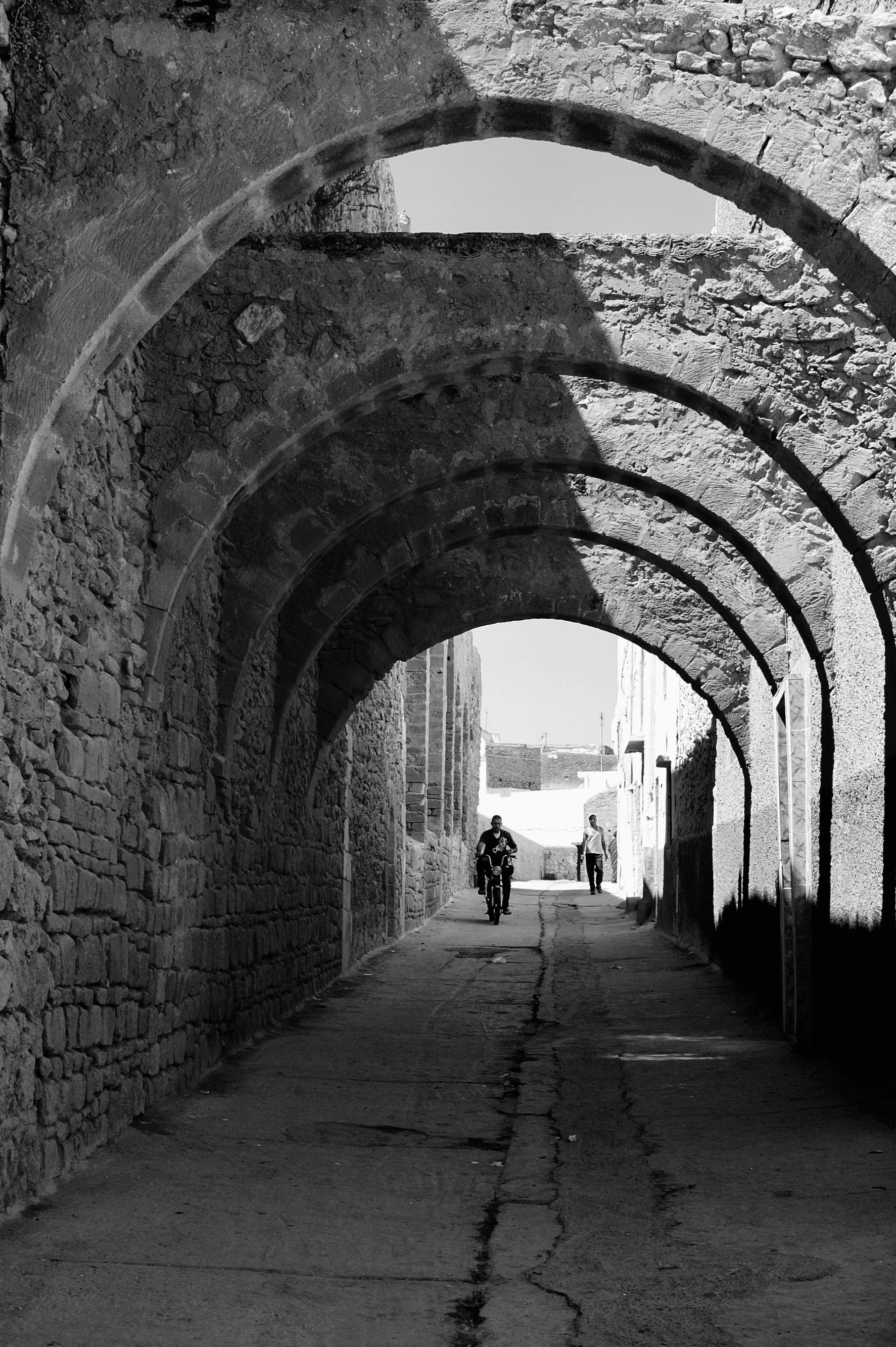 бесплатная Черно-белая фотография каменной арки с силуэтом велосипедиста. Стоковое фото