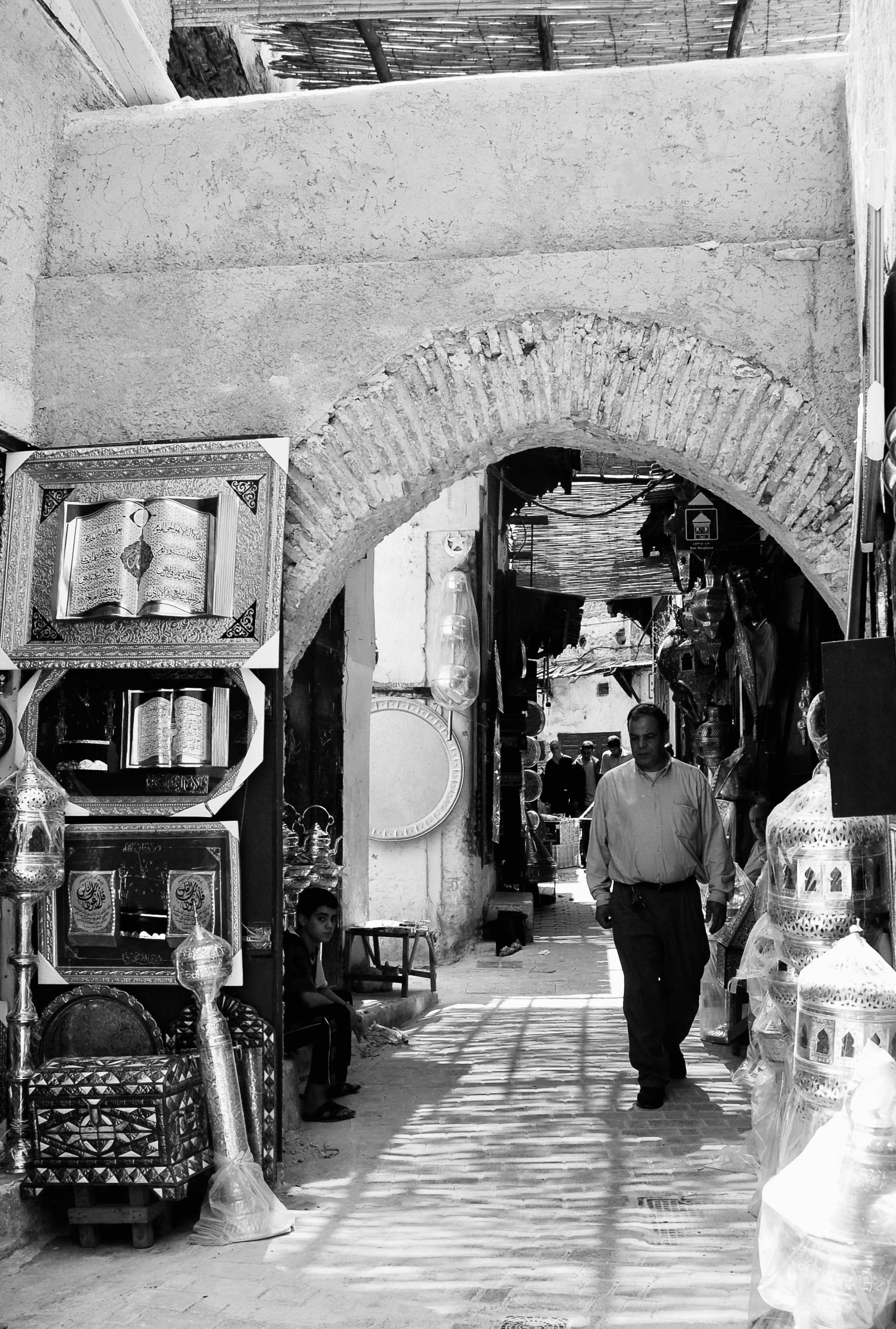 бесплатная Мужчина прогуливается по улочке старинного базара, где представлены традиционные ремесла и предметы искусства. Стоковое фото