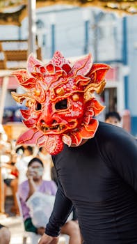 A person wearing an intricate red mask at an outdoor festival, capturing cultural spirit.