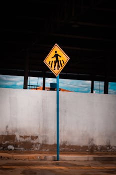 A vibrant pedestrian crossing sign against an industrial urban backdrop.