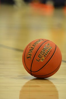 Spalding basketball resting on shiny indoor court floor, focus on ball.